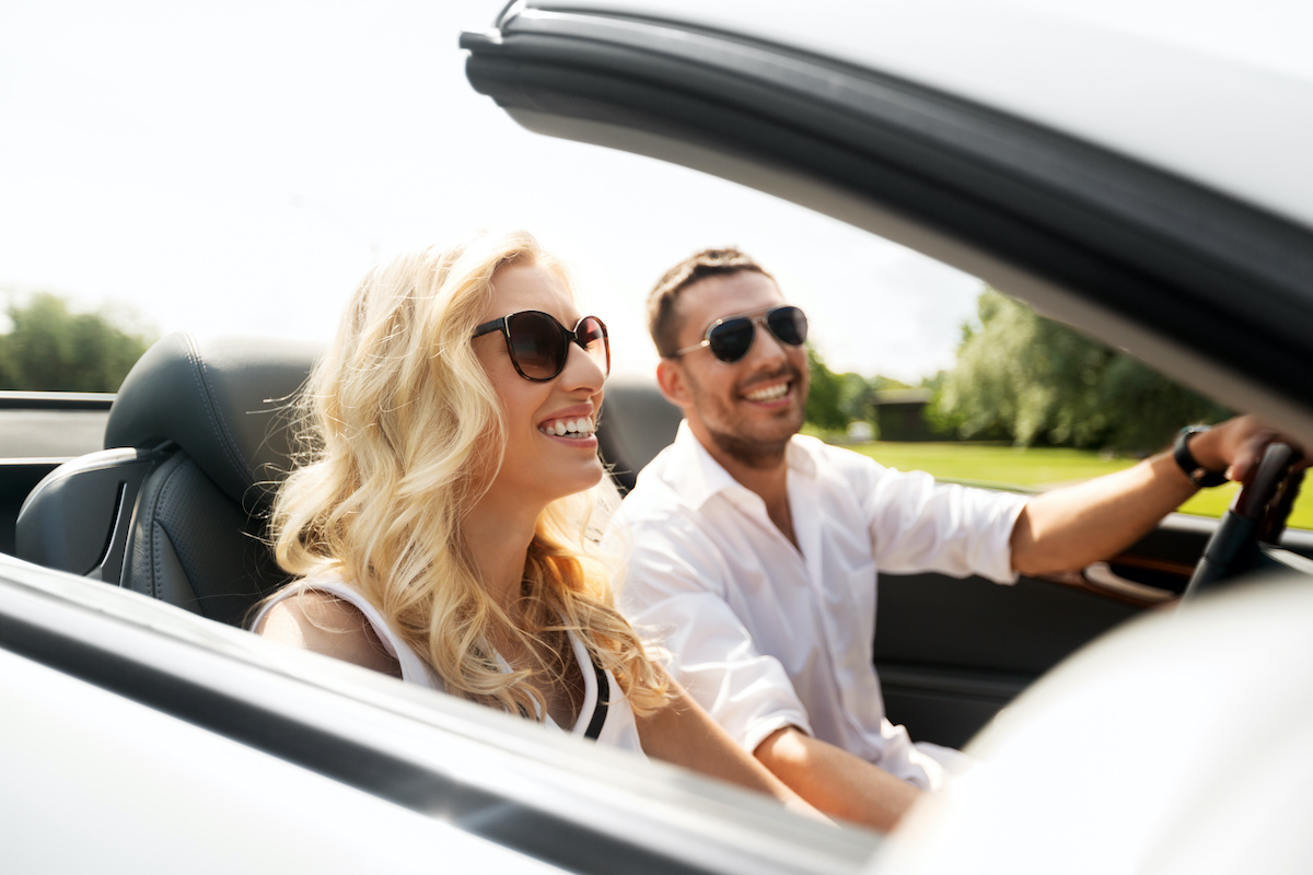 happy man and woman driving in cabriolet car